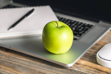 İş yerinde laptopun yanında yeşil elma, işte sağlıklı atıştırmalıklar..