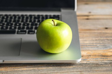 İş yerinde laptopun yanında yeşil elma, işte sağlıklı atıştırmalıklar..