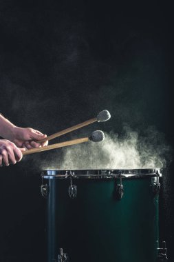 Bir adam siyah arka planda sopalarla bir müzik enstrümanı çalar. Trampetli bir müzik konsepti, güzel sahne ışıklandırması..