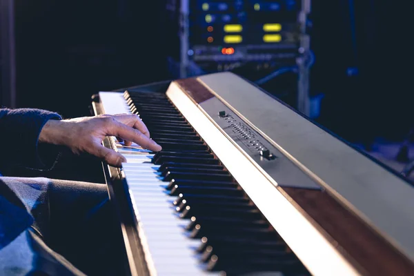 A man plays the electronic piano on stage or in a recording studio, hands close-up.