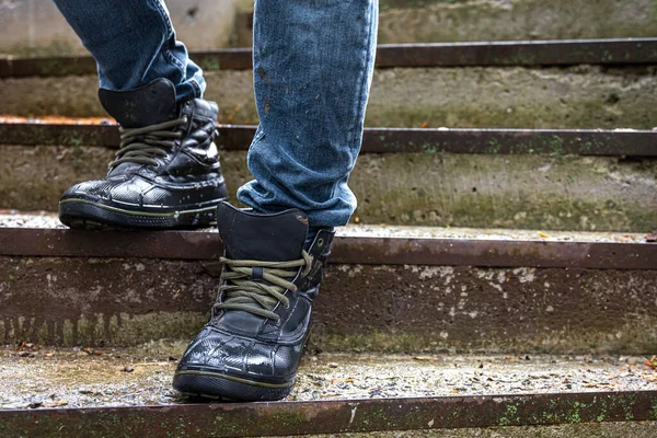 A man in wet boots on old steps, legs close-up.
