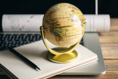 Tahta masaüstünde dünya, dizüstü bilgisayar ve not defteri ile seyahat bileşimi.