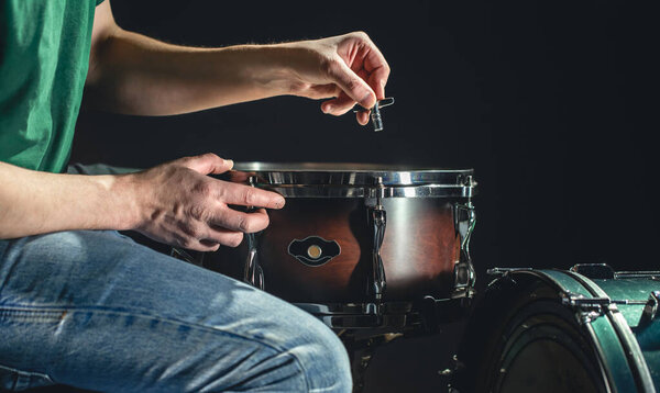 A male drummer plays the snare drum on a dark background, a musical percussion instrumentman.