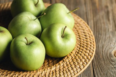 Yakın plan, saman tabaktaki yeşil elmalar ahşap arka planda, kırsal tarzda..