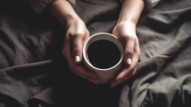 Beyaz kahve, kadın ellerinde, arka planda koyu bir battaniye, yakın plan..