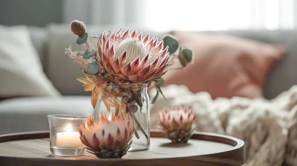 Home composition with exotic protea flower and candles on blurred room interior background.
