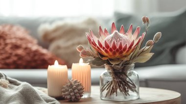 Egzotik protea çiçekli ev kompozisyonu ve bulanık oda arka planında mumlar..