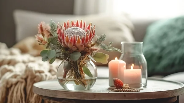 Home composition with exotic protea flower and candles on blurred room interior background.