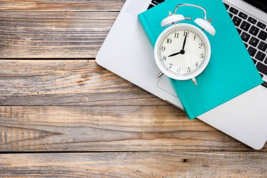 Diz üstü, mavi kitap ve beyaz alarm saati ahşap zemin, üst görünüm, işyeri konsepti, kopyalama alanı.