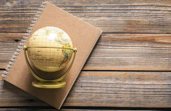 stock image Earth globe and notebook on wooden background, top view, copy space.