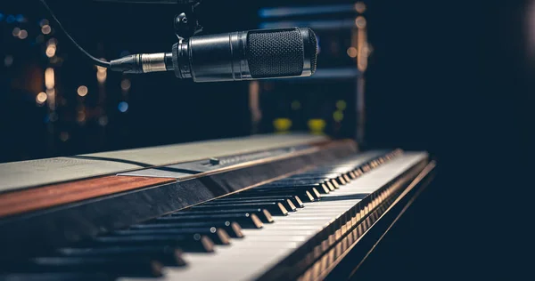 stock image Musical keys and a microphone on a dark background, an electronic piano on stage or in a music studio.