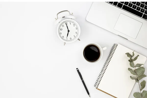 stock image Minimalistic white background with laptop, notepad, alarm clock and black coffee cup, top view, copy space.