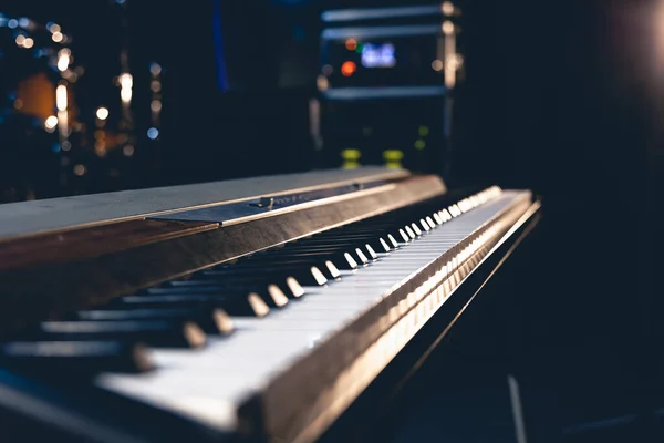 stock image Keys of an electronic piano close-up on a dark background with stage lighting.