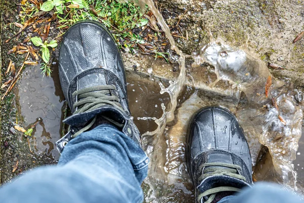 View from above on pair of trekking shoes in a mud, reliable shoes for bad weather.