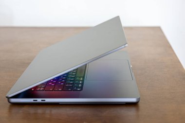 Ahşap bir masada yarı kapalı dizüstü bilgisayar, ekran renklerle parlıyor, iş konsepti.