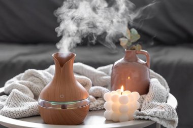 Odanın içinde bulanık bir arka planda aroma yağı yayıcı lamba ve mum içeren spa kompozisyonu.