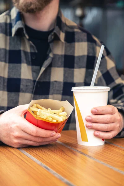 stock image Close-up, french fries and a drink in male hands in a fast food cafe, an unhealthy snack.