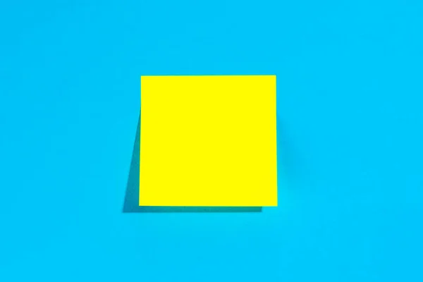 stock image Yellow note with empty place for text on a blue background, copy space, flat lay.