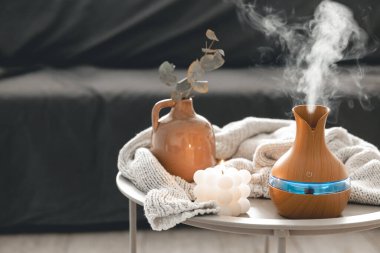 Odanın içinde bulanık bir arka planda aroma yağı yayıcı lamba ve mum içeren spa kompozisyonu.