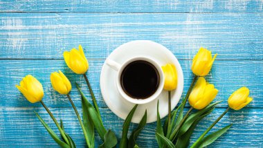 Sarı lale buketi ve mavi ahşap arka planda bir fincan kahve..