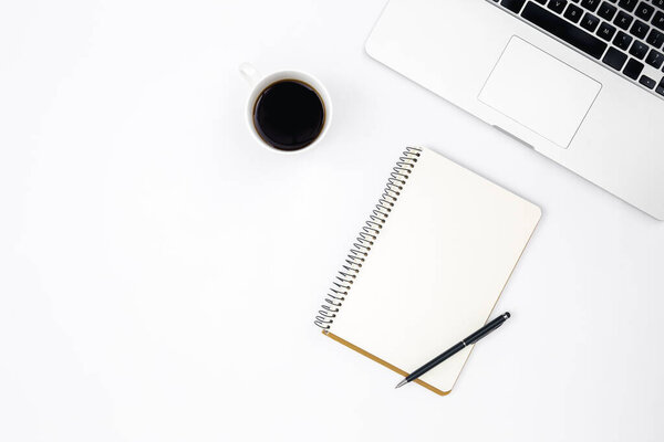 Minimalistic white background with laptop, notebook and cup of black coffee, top view, copy space.