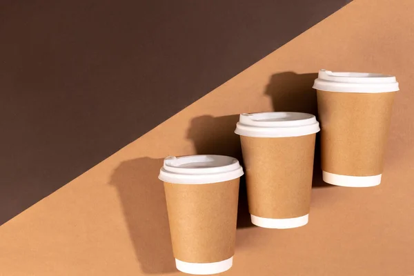 stock image Disposable paper cups for hot drinks on a brown background, top view. The concept of ecology, zero waste.