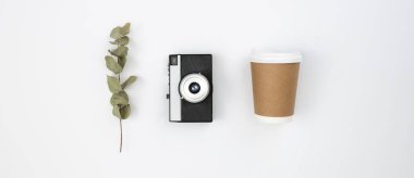 Retro kamera, okaliptüs dalı ve beyaz arka planda tek kullanımlık kağıt bardak. En küçük arkaplan.