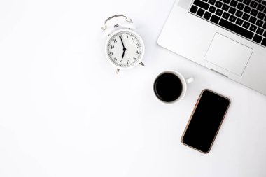 Dizüstü bilgisayarı, akıllı telefonu, çalar saati ve siyah kahve fincanı olan minimal beyaz arkaplan, üst görünüm, boşluk kopyala.