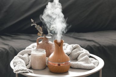 Odanın içinde bulanık bir arka planda aroma yağı yayıcı lamba ve mum içeren spa kompozisyonu.