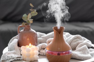 Odanın içinde bulanık bir arka planda aroma yağı yayıcı lamba ve mum içeren spa kompozisyonu.