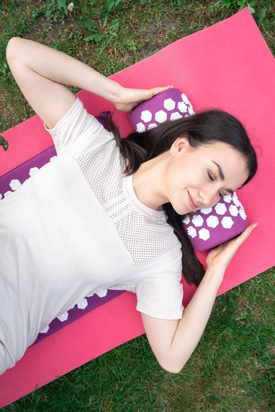 Acupuncture massage mat with pillow. A woman lies on a massage mat.Concept of alternative medicine. Acupuncture massage mat with pillow.