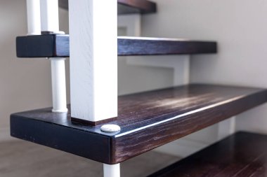 Yakın plan, kahverengi ve beyaz boyalı ahşap basamaklar bir evin içinde.