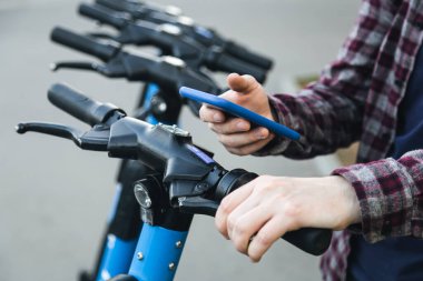 Mobil uygulama kullanarak insan elinin kapatılması, sokakta kiralık elektrikli scooter için QR kodu taraması, ulaşım konsepti.