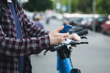 Mobil uygulama kullanarak insan elinin kapatılması, sokakta kiralık elektrikli scooter için QR kodu taraması, ulaşım konsepti.