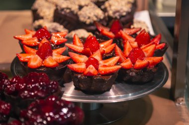 Pencerede çilekli tatlılar var. Dükkanda hamur işleri olan bir vitrin. Tatil için dolapta şeker var..