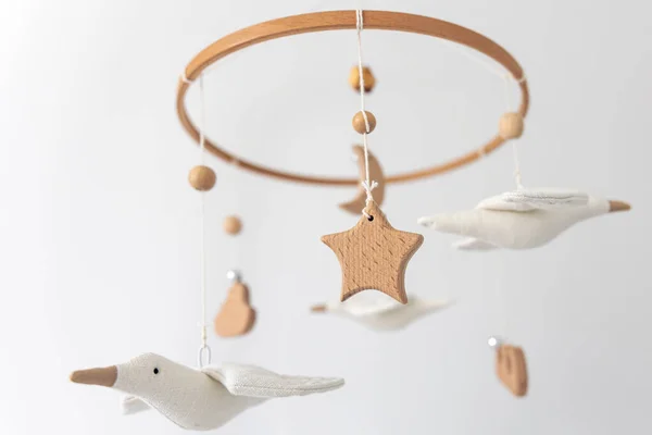 Kids handmade toys above the newborn crib, first baby eco-friendly toys made from felt and wood.