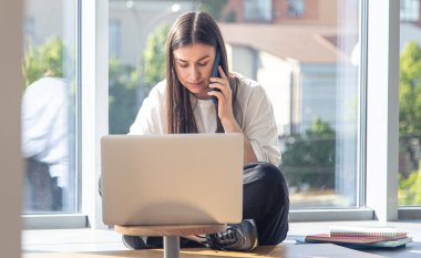 Bilgisayarın önündeki yorgun genç kadın ofisin penceresinin yanındaki akıllı telefondan konuşuyor, boşluğu kopyalıyor..