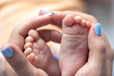 Anne yeni doğmuş bir bebeğin bacaklarını elinde tutuyor, yakın plan, yumuşak odaklanma, annelik ve bakım kavramı..