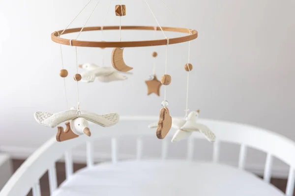 Kids handmade toys above the newborn crib, first baby eco-friendly toys made from felt and wood.