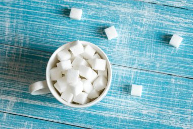 Mavi ahşap bir yüzeyde beyaz şeker küpleri, yakın plan, rafine şeker, şeker, şeker, tatlı içecek konsepti.