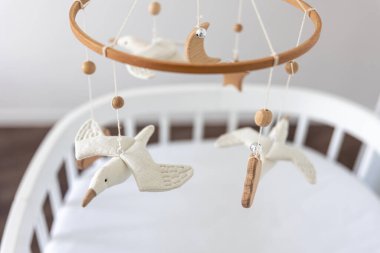 Çocuklar yeni doğan beşiğin üstünde el yapımı oyuncaklar, keçe ve ahşaptan yapılmış ilk bebek çevre dostu oyuncaklar..