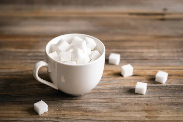Cup with sugar cubes on a wooden surface, close-up, pressed refined sugar, diabetes, sweet drinks concept.