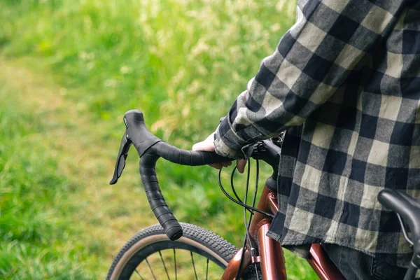 Bir Adam Bir Bisikletin Direksiyonunu Tutar Ormanda Yeşil Çimlerin Arasında — Stok fotoğraf