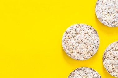 Sarı arka planda pirinç keklerinden yapılmış yaratıcı düzen, düz yatak, gıda konsepti.