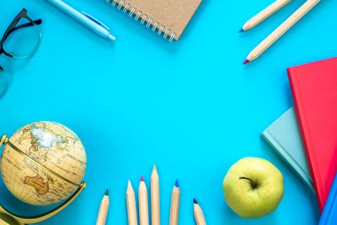 Açık mavi arka planda renkli eğitim malzemeleriyle düz bir zemin oluşturuldu, okul konseptine geri döndü, kopyalama alanı.