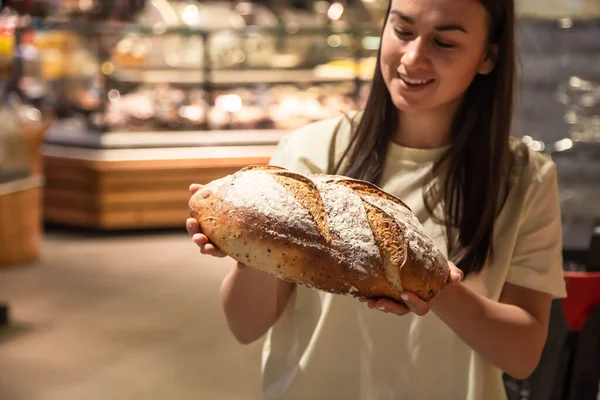 stock image A loaf of freshly baked bread in female hands in a bakery.