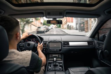 A male driver drives at speed through the streets of the city, a view from inside the car.