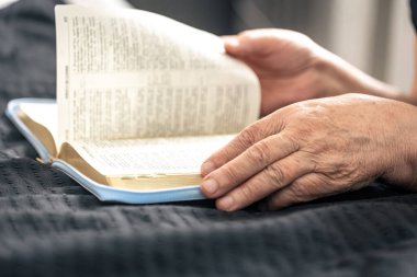 Yaşlı bir kadın İncil 'i, el ve yakın çekim kitabını okur. Tanrı' ya ve dini hayata olan inanç kavramını..