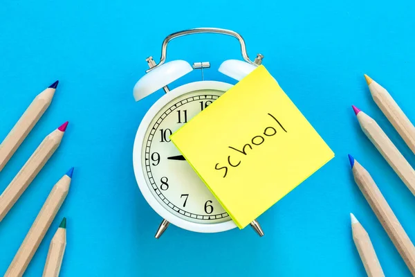 アラームクロック 青の背景に単語の学校や鉛筆で紙のリマインダー クローズアップ — ストック写真