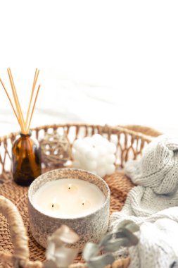 Aroma yağı yayıcı lambalı spa kompozisyonu ve bulanık bir arka planda hasır tepside mum..